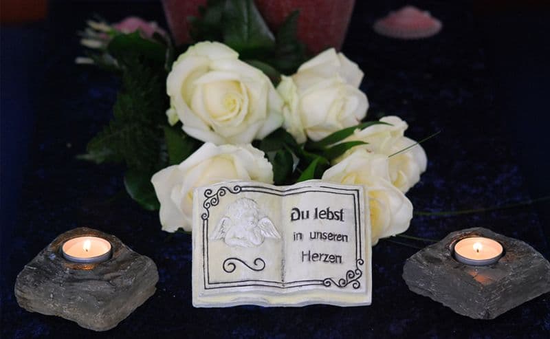 Kleiner Strauß weißer Blumen mit Buch und zwei Kerzen davor